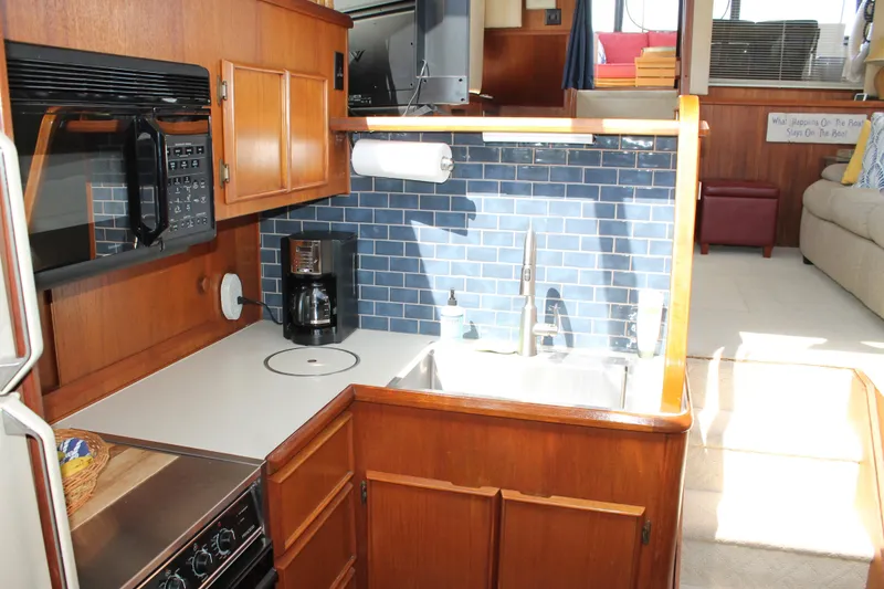 Slide: The Image of 1987 Chris-Craft 427 Catalina yacht kitchen with wood cabinetry and blue tile backsplash. - 33