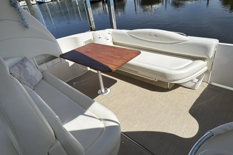Slide: The Image of 2002 Sea Ray 360 Sundancer boat interior with white seating and wooden table. - 10