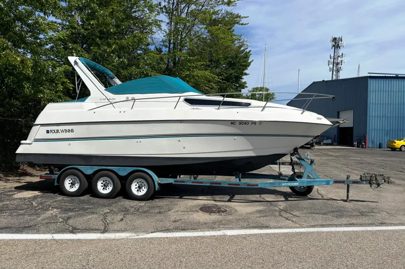 Slide: The Image of 1994 Four Winns 278 Vista boat on trailer, parked outdoors near trees and industrial buildings. - 1