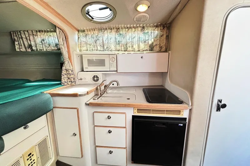Slide: The Image of 1994 Four Winns 278 Vista boat interior with kitchenette, sink, microwave, and compact fridge. - 16
