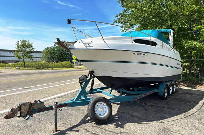Slide: The Image of 1994 Four Winns 278 Vista boat on trailer, parked roadside under clear blue sky. - 2