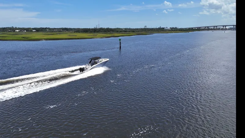 Slide: The Image of A 2027 Sea Ray SDX 290 Outboard speeds across a wide river under a blue sky. - 24