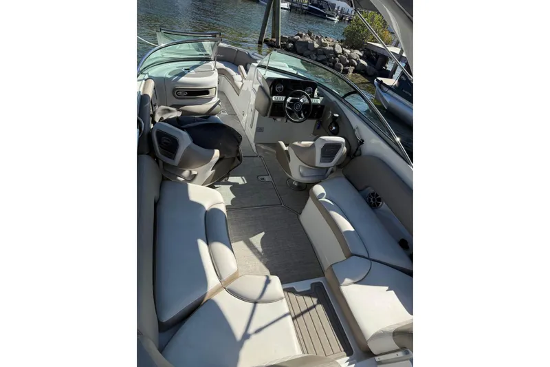 Slide: The Image of 2022 Crownline 265 SS boat interior with plush seating and modern dashboard, docked by the water. - 3