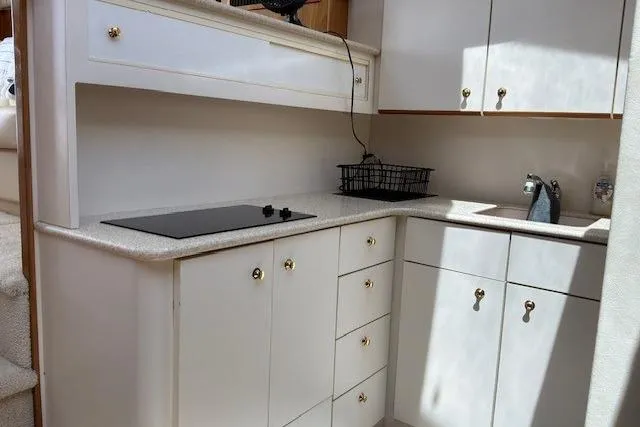 Slide: The Image of Kitchen area of a 2000 Silverton 41 Convertible yacht with white cabinetry and stovetop. - 13