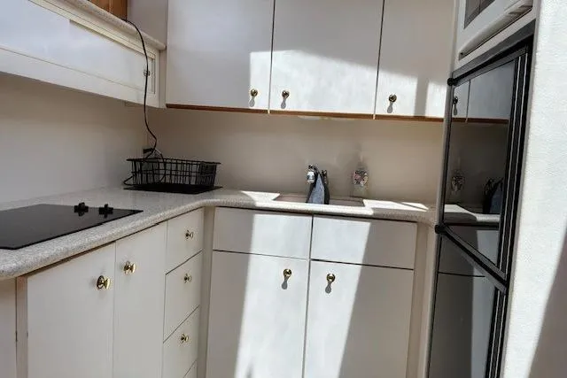 Slide: The Image of Kitchen area of a 2000 Silverton 41 Convertible yacht with white cabinets and appliances. - 14