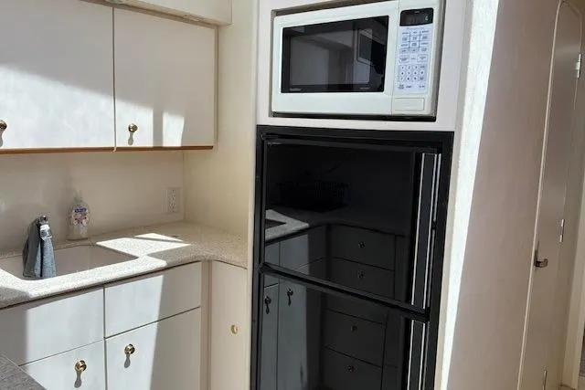 Slide: The Image of Kitchen area of a 2000 Silverton 41 Convertible yacht with microwave and fridge. - 15
