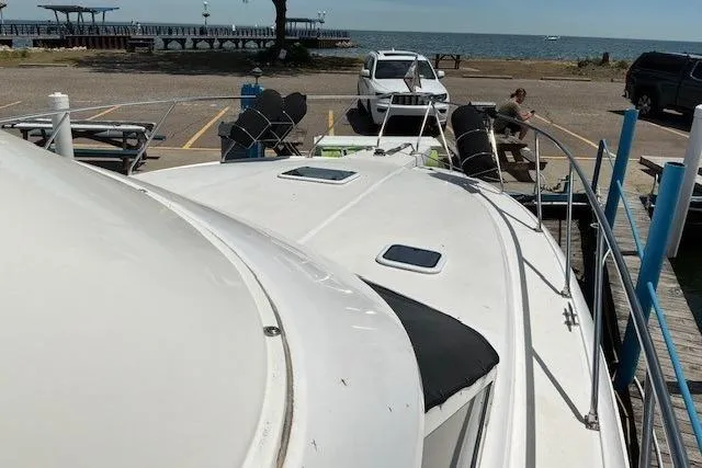 Slide: The Image of 2000 Silverton 41 Convertible yacht docked near a waterfront with parked vehicles. - 2