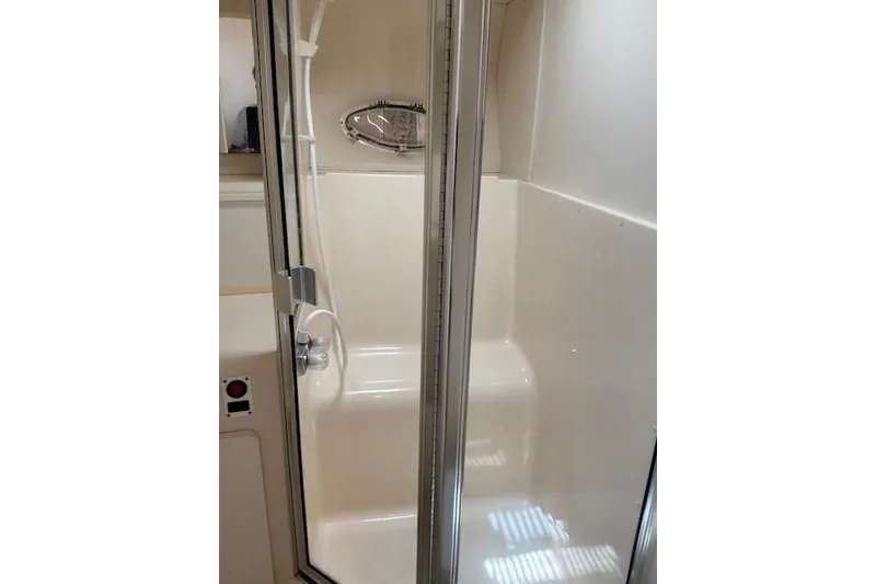 Slide: The Image of Shower area inside a 2000 Silverton 41 Convertible yacht, featuring a glass door. - 23