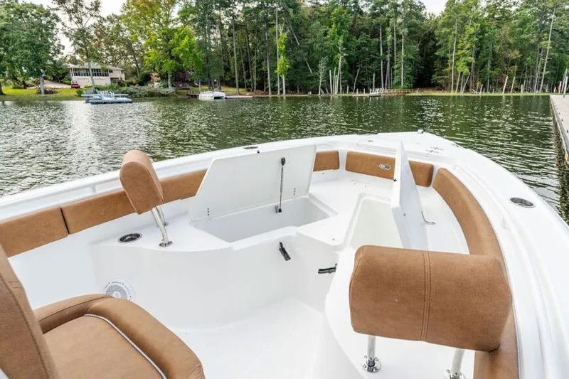 Slide: The Image of Manufacturer Provided Image: 2026 Sea Hunt Ultra 235 SE boat interior with brown seating, docked by a scenic lake. - 16