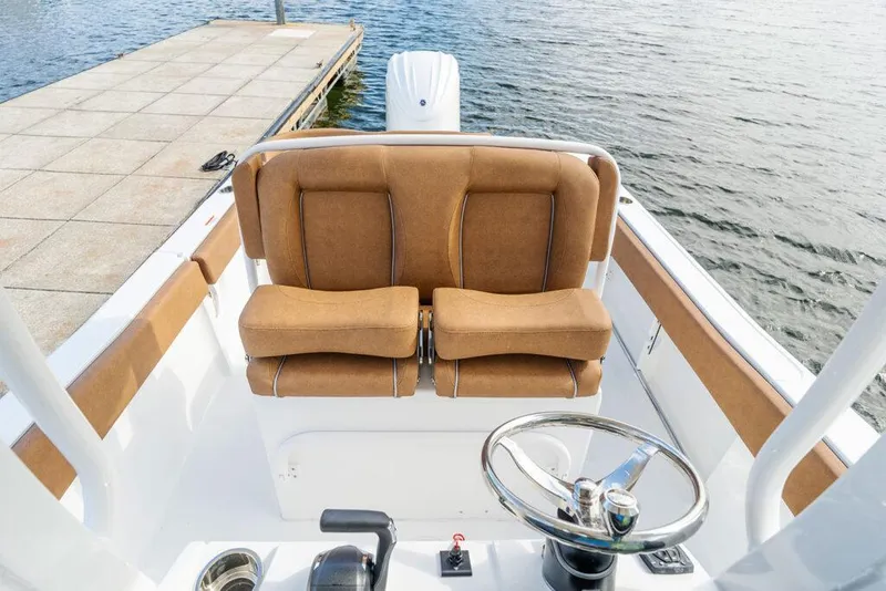 Slide: The Image of Manufacturer Provided Image: 2026 Sea Hunt Ultra 235 SE boat interior with tan seating and steering wheel by the dock. - 18