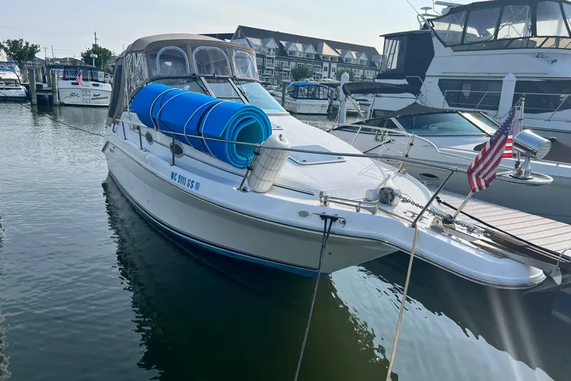 Slide: The Image of 1997 Sea Ray 270 Sundancer docked at marina with American flag and blue floatation rolls. - 4