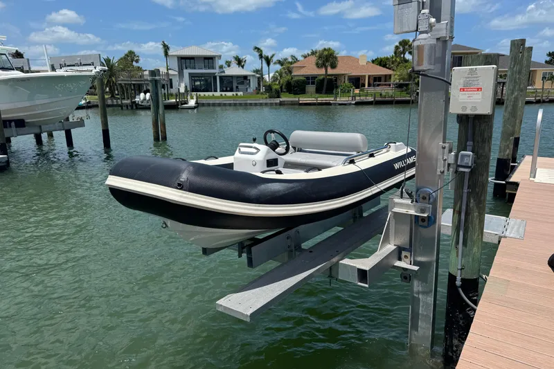 Slide: The Image of 2025 Williams Jet Tenders Sportjet 345 on a lift by waterfront homes. - 1