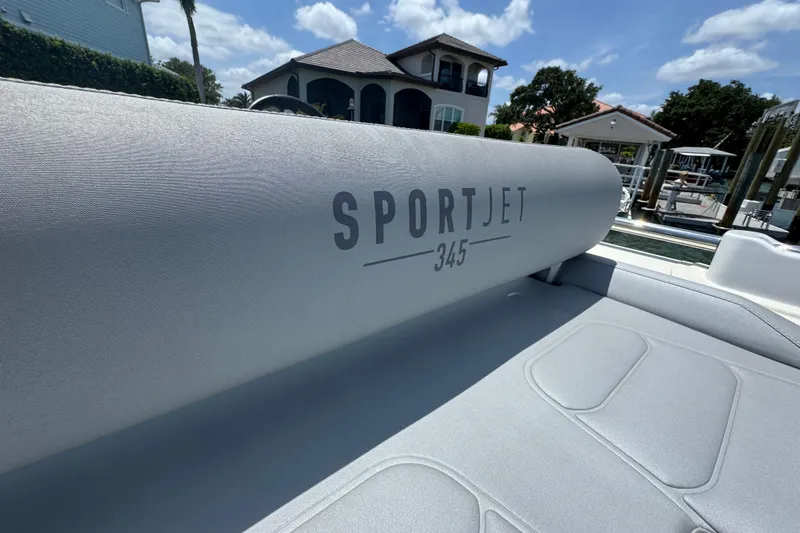 Slide: The Image of 2025 Williams Jet Tenders Sportjet 345 boat interior with logo, docked near luxury homes. - 5