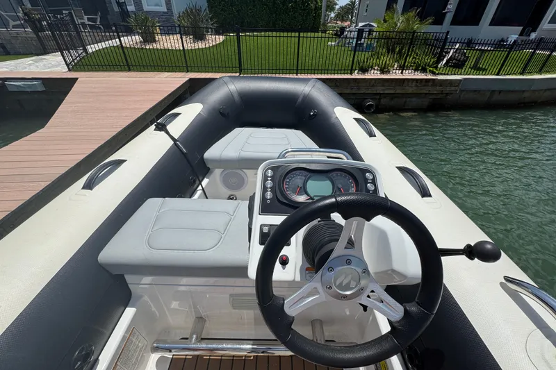 Slide: The Image of 2025 Williams Jet Tenders Sportjet 345 interior with steering wheel and dashboard, docked by water. - 7