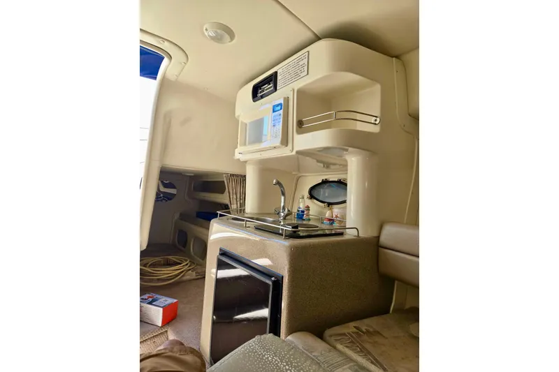 Slide: The Image of 1999 Rinker Fiesta Vee 270 cabin interior with kitchenette and seating area. - 14
