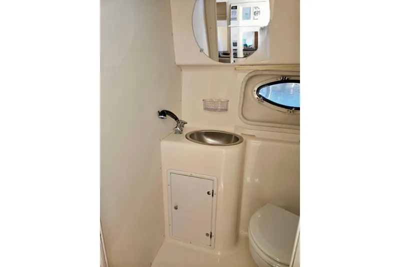 Slide: The Image of 1999 Rinker Fiesta Vee 270 boat bathroom with sink, toilet, and porthole window. - 18