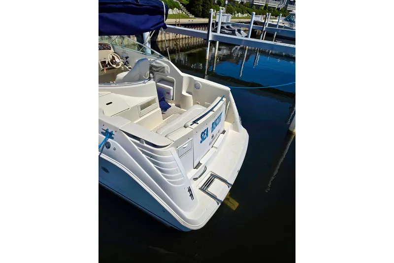 Slide: The Image of 1999 Rinker Fiesta Vee 270 boat docked, showcasing rear deck and seating area. - 4