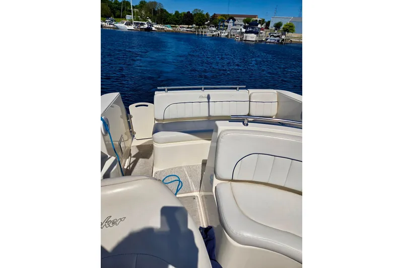 Slide: The Image of 1999 Rinker Fiesta Vee 270 boat interior with white seating, docked by a marina. - 6