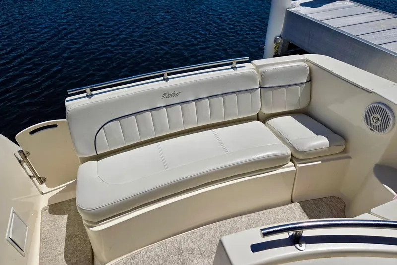 Slide: The Image of 1999 Rinker Fiesta Vee 270 boat interior with white cushioned seating by the water. - 8