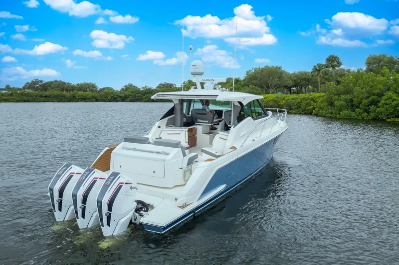 Slide: The Image of 2021 Tiara Sport 43 LE boat cruising on a scenic waterway under a blue sky. - 10