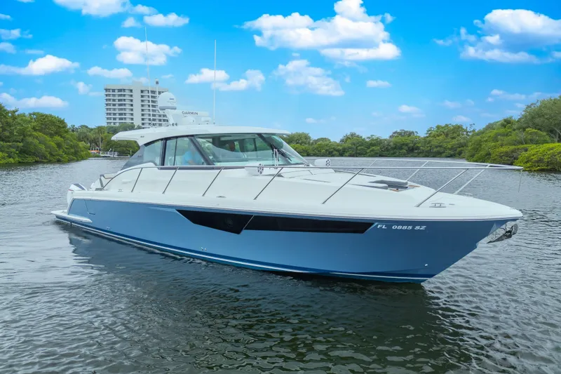 The Image of 2021 Tiara Sport 43 LE yacht cruising on a scenic waterway under a clear blue sky. - 7