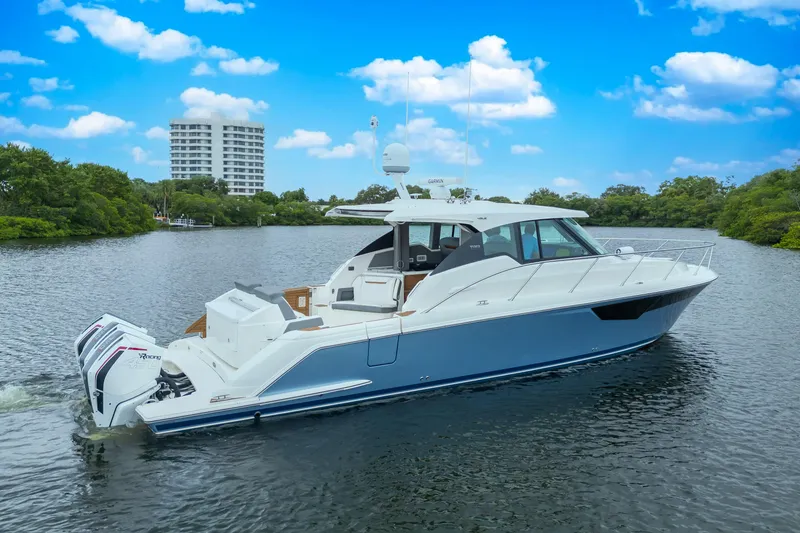 Slide: The Image of 2021 Tiara Sport 43 LE yacht cruising on a scenic river under a blue sky. - 9