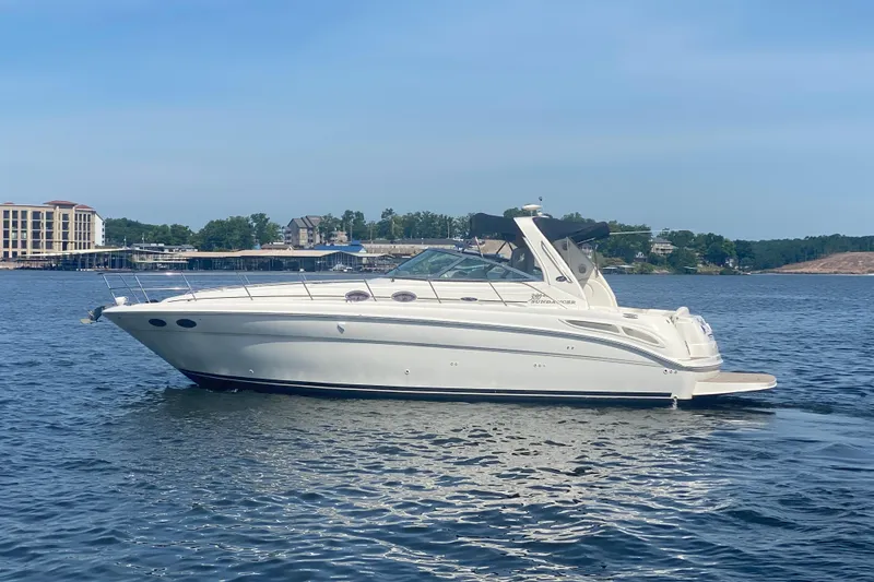 The Image of 2004 Sea Ray 380 Sundancer yacht cruising on a serene lake under a clear blue sky. - 1