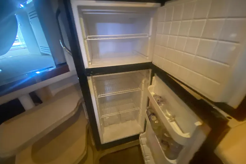 Slide: The Image of Open refrigerator inside 2004 Sea Ray 380 Sundancer yacht, showing shelves and door storage. - 27
