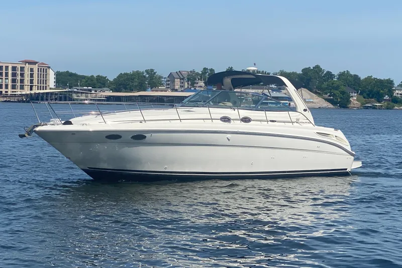 Slide: The Image of 2004 Sea Ray 380 Sundancer yacht on calm water, with scenic shoreline background. - 3