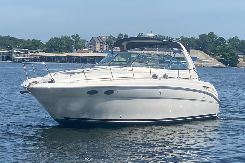 Slide: The Image of 2004 Sea Ray 380 Sundancer yacht on calm water, with scenic shoreline background. - 4