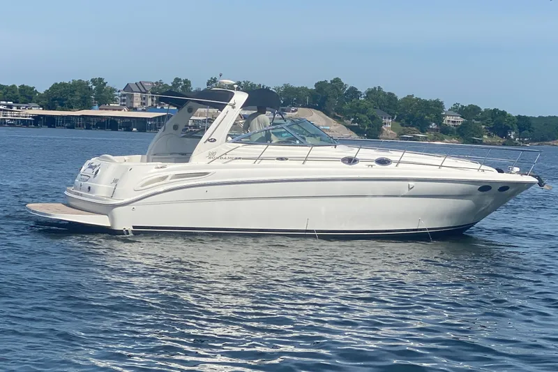 Slide: The Image of 2004 Sea Ray 380 Sundancer yacht on calm water, surrounded by scenic shoreline. - 7