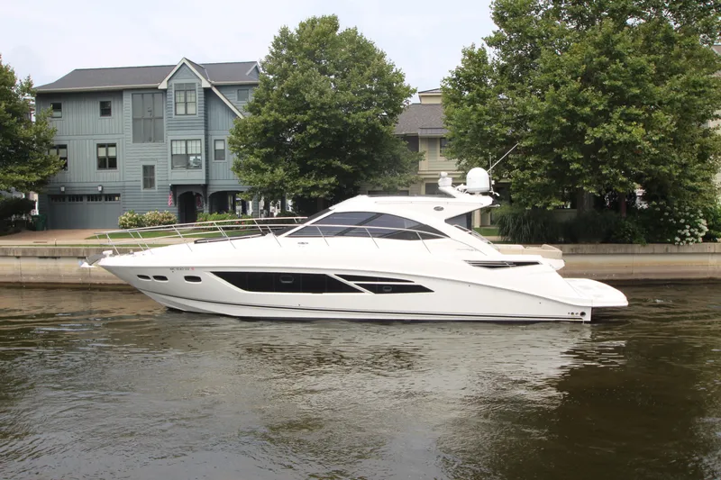 The Image of 2016 Sea Ray 510 Sundancer yacht docked by waterfront homes and trees. - 0