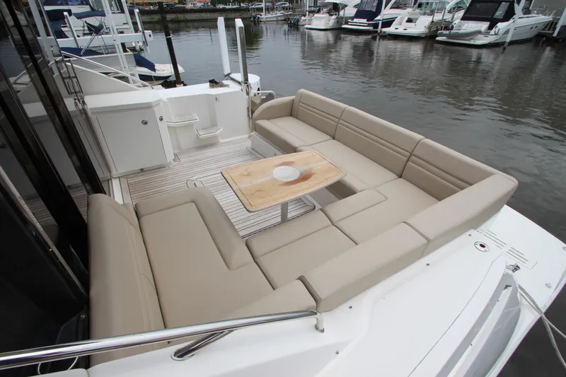 Slide: The Image of 2016 Sea Ray 510 Sundancer yacht with spacious outdoor seating and table, docked at marina. - 14