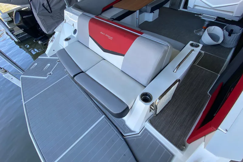 Slide: The Image of 2014 Cruisers 328 Black Diamond boat interior with gray and red seating, cup holders, and deck view. - 13