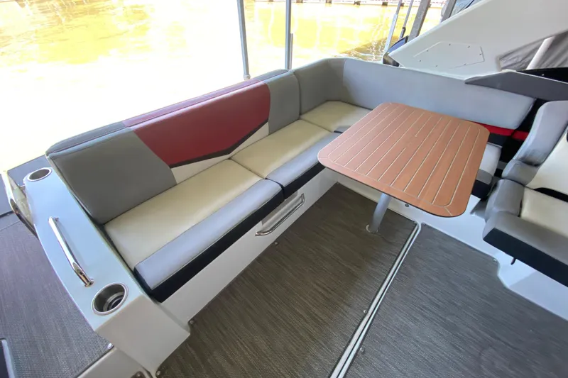 Slide: The Image of 2014 Cruisers 328 Black Diamond boat interior with cushioned seating and wooden table. - 17