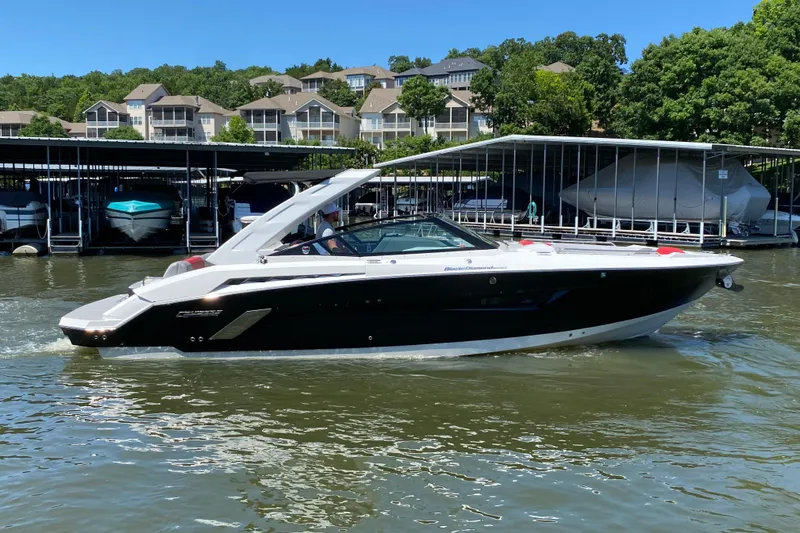 Slide: The Image of 2014 Cruisers Sport Series 328 Black Diamond boat on a sunny lake near docks. - 3