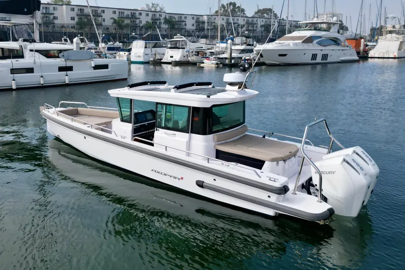 The Image of 2023 Axopar 28 Cabin boat docked in a marina, surrounded by other vessels. - 0
