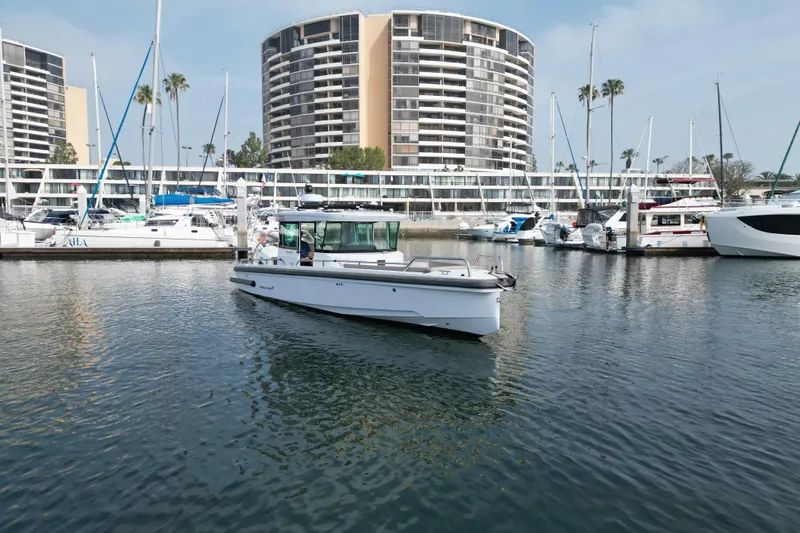 Slide: The Image of 2023 Axopar 28 Cabin boat in marina with modern buildings in background. - 7