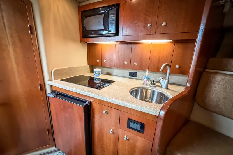 Slide: The Image of Compact kitchen area in a 2006 Rampage 33 Express boat with wood cabinetry. - 11