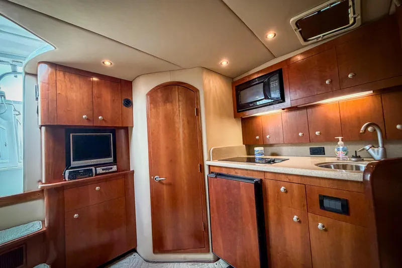 Slide: The Image of 2006 Rampage 33 Express yacht interior with kitchenette, wood cabinets, microwave, and compact appliances. - 13