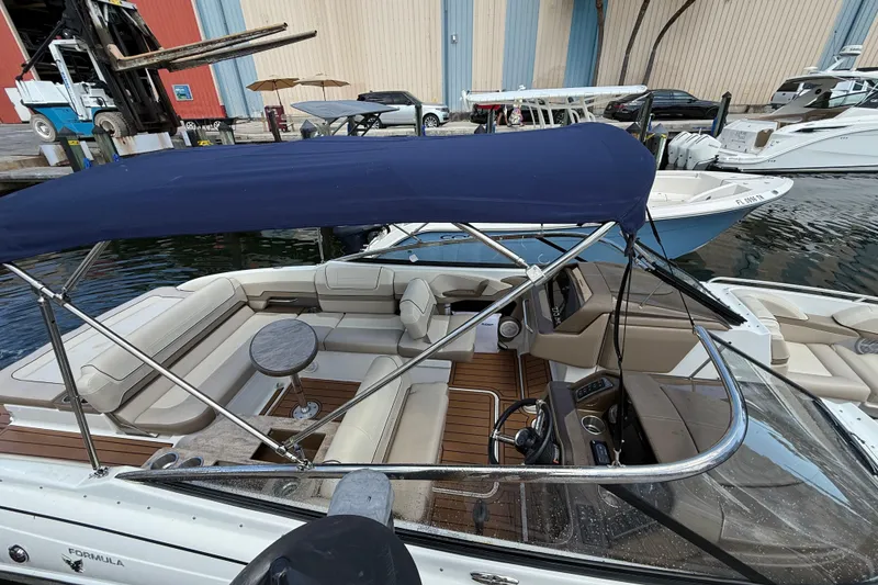 Slide: The Image of 2019 Formula 270 Bowrider with blue canopy, docked at marina, featuring spacious seating. - 7