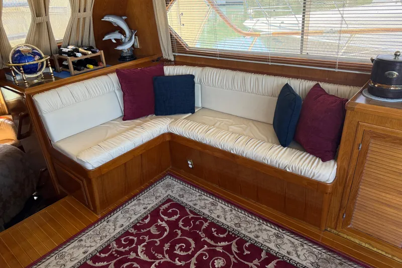 Slide: The Image of Cozy 1987 PT Sundeck yacht interior with cushioned seating, decorative pillows, and elegant decor. - 13