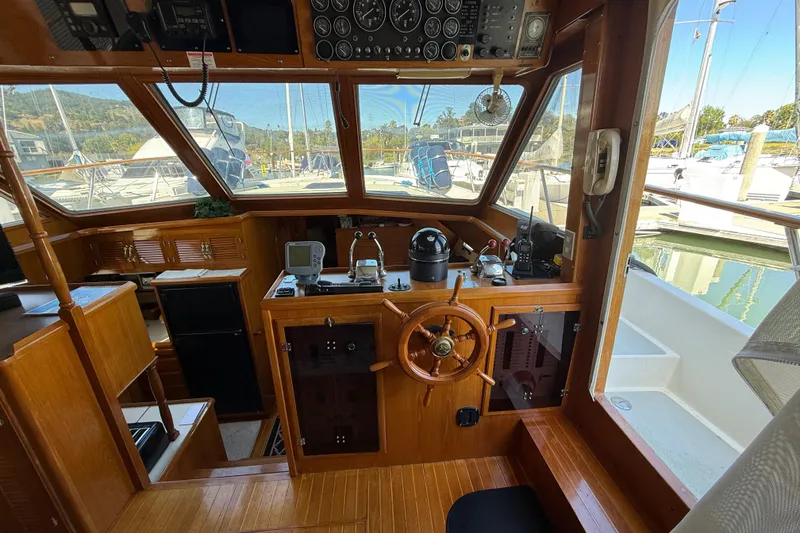 Slide: The Image of 1987 PT Sundeck boat interior with wooden helm, navigation instruments, and marina view. - 16