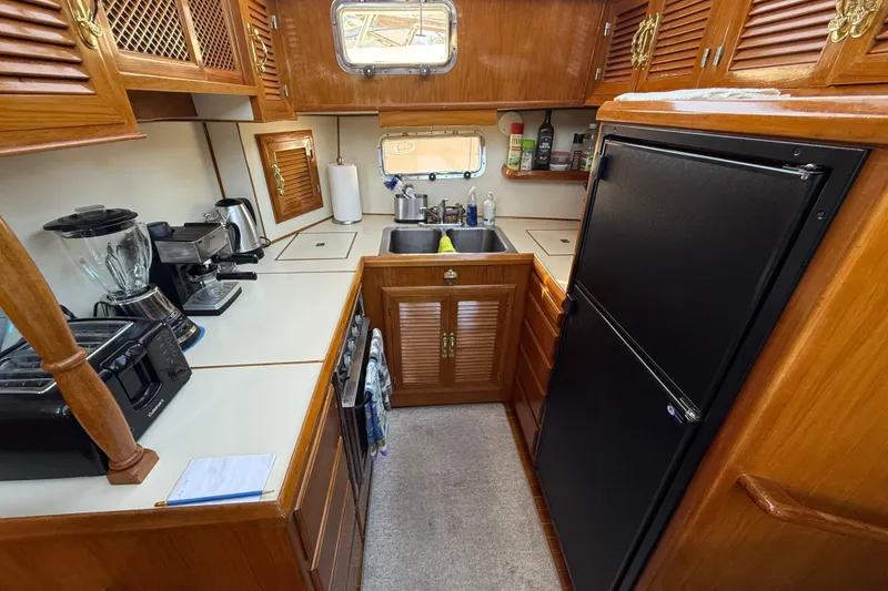 Slide: The Image of 1987 PT Sundeck yacht kitchen with wooden cabinets, appliances, and a compact layout. - 21