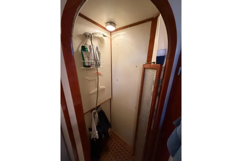 Slide: The Image of Compact shower area in a 1987 PT Sundeck boat, featuring wooden trim and storage shelves. - 36