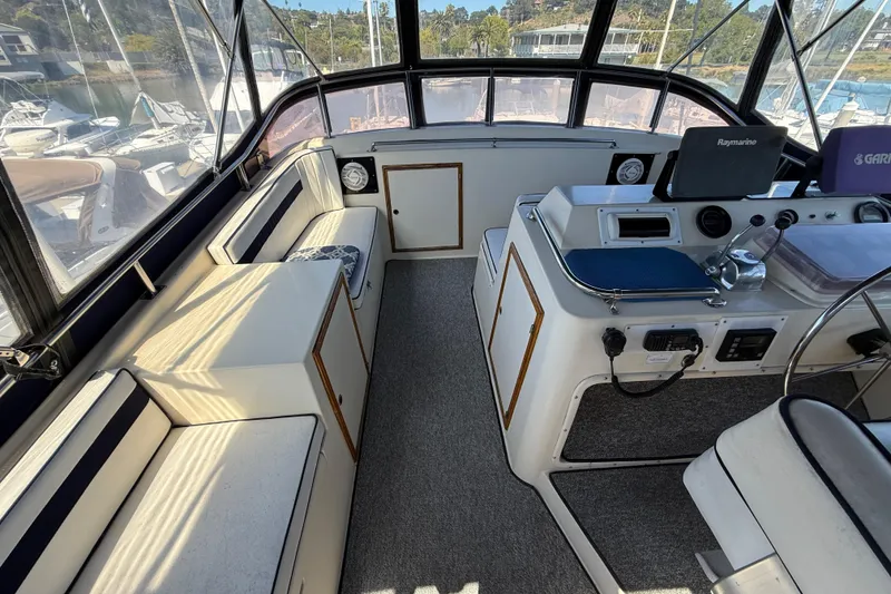 Slide: The Image of 1987 PT Sundeck boat interior with helm, seating, and navigation equipment in a marina setting. - 4