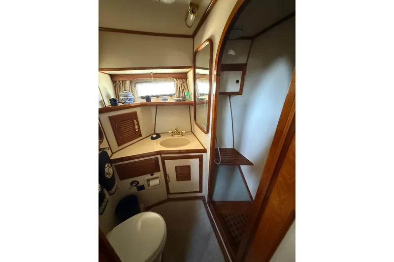 Slide: The Image of 1987 PT Sundeck yacht bathroom with wooden accents, sink, mirror, and shower area. - 40