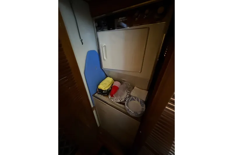Slide: The Image of Laundry area inside 1987 PT Sundeck boat, featuring a washing machine and storage space. - 41