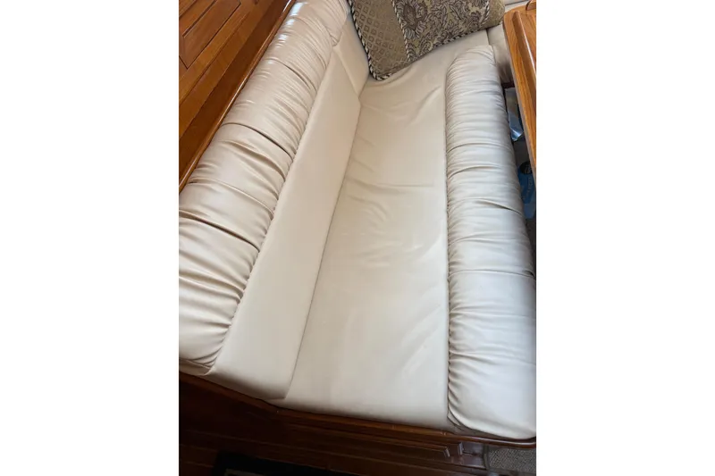 Slide: The Image of Cream leather seating on 1987 PT Sundeck boat, featuring wooden accents and decorative cushion. - 43