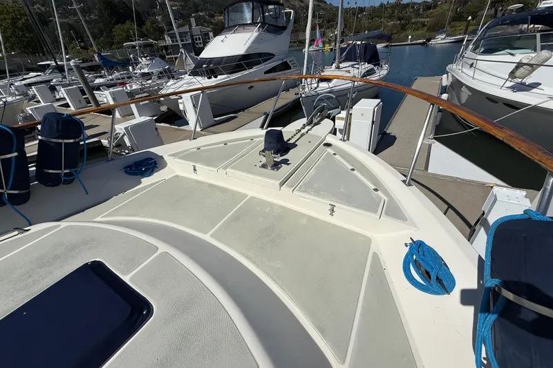 Slide: The Image of 1987 PT Sundeck yacht docked at marina, featuring spacious deck and moored boats. - 57